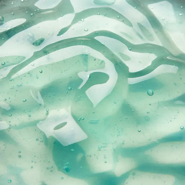 Close-up of a translucent aqua blue gel with swirls, bubbles, and smooth textures, creating an abstract, fluid appearance.