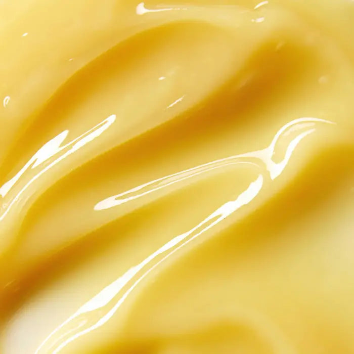 Close-up of a smooth, glossy, yellow substance with creamy texture and shiny highlights, possibly custard, pudding, or cream.