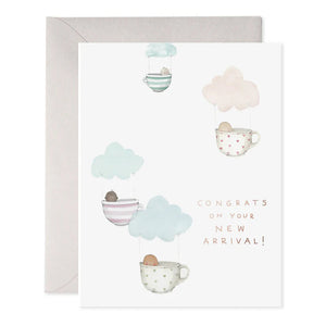 The TEACUP BABIES GREETING CARD by E.FRANCES PAPER showcases a handcrafted watercolor design with soft pastels, depicting four mugs hanging from clouds with little brown shapes. It includes the message, "Congrats on your new arrival!" and comes with a simple grey envelope, offering a delightful touch to baby-themed illustrations.