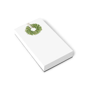 Introducing the WREATH NOTEPAD by E.FRANCES PAPER: This substantial notepad, crafted in the USA, boasts a clean rectangular format with an elegant green wreath illustration adorning the top, set on a simple white background—ideal for all your note-taking requirements.