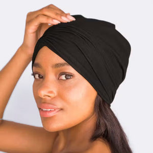 Packaging for the SLEEP BEANIE WITH SATIN LINING by KITSCH. The primarily white box features a cut-out displaying the black beanie inside. It advertises "Bye Bye Bedhead" and highlights that it’s "Seriously, SO SOFT!" Designed to prevent hair breakage, a small image shows a person wearing the jersey bonnet.