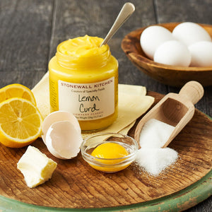 A glass jar with a dark green lid contains STONEWALL KITCHEN - LEMON CURD. The label reads "STONEWALL KITCHEN Creators of Specialty Foods, Lemon Curd, COMPANY CLASSIC, GLUTEN FREE, Net Weight 326g (11.5 oz.)." The curd is yellow and offers the sweet tartness of traditional English-style custard.