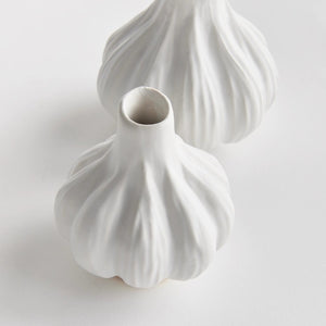 The NAPA HOME AND GARDEN - ALBURY BUD VASE features two white ceramic vases on a plain white background. Their reactive glaze, bulbous shapes, and narrow openings resemble garlic bulbs, showcasing the artisan's craftsmanship.