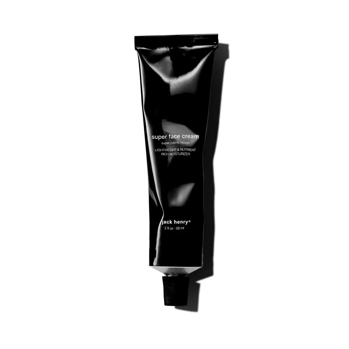 A black tube of JACK HENRY - SUPER FACE CREAM, branded with &quot;JACK HENRY&quot; in white text and topped with a black cap, rests on a white background casting a right-side shadow—a minimalist moisturizer ideal for anti-aging skincare.