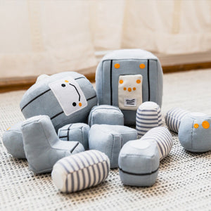 Description: Meet the TOT BOT from WONDER AND WISE ASWEETS, an educational toy designed to delight and educate. With its light gray body, segmented arms and legs, and cheerful yellow accents, this plush robot is sure to captivate. The friendly face sports black eyes and a happy smile, while the rectangular torso is adorned with colorful buttons and charming striped patterns on its limbs.