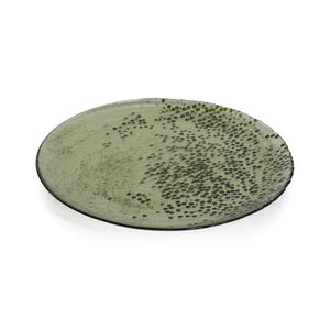 The DOTTED GLASS PLATE 11" by ZODAX is a round ceramic plate with an 11-inch diameter and a green glazed finish. Its surface displays a pattern of small, raised dots that are concentrated on the right side and gradually spread towards the center. The edges of this meticulously crafted plate are slightly uneven.