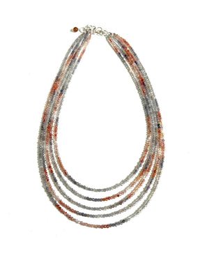 Introducing the ANN LIGHTFOOT - FIVE STRAND IOLITE AND CARNELIAN STRAND NECKLACE, a beautifully crafted piece showcasing multi-strand elegance with small beads in shades of red, grey, and white. The strands are gracefully layered, enhanced with carnelian accents, and secured with a silver clasp for a sophisticated finish.