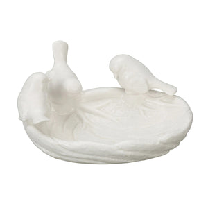 The LEAF DISH WITH BIRDS by CREATIVE COOP is a white ceramic trinket holder designed to resemble a bird bath, featuring three birds perched on the edge. The surface has intricate detailing that mimics the texture of a real bird bath.