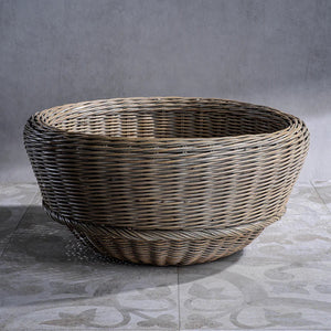 The MONTEVERDE RATTAN BOWL by ZODAX is a round, empty wicker basket featuring a light brown finish. Measuring 18.5 in x 9 in, this basket showcases a tightly woven pattern with a slightly flared rim and a bottom that is slightly raised off the surface. It is displayed against a plain white background.