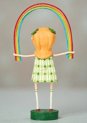 The ESC AND COMPANY - RAINBOW BRIGHT FIGURINE by ESC AND COMPANY, INC is a 7" poly resin piece featuring an orange-haired girl in a green and white checkered dress with four-leaf clovers, holding a vibrant rainbow above her head while standing on a green base in knee-high socks.