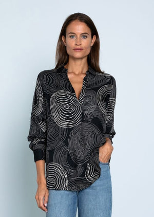 A long-sleeved, black blouse with a collar, showcasing an intricate pattern of white dotted concentric circles in various sizes. Made from flowing viscose material, the Derry Long Sleeve Viscose Blouse by 0039 ITALY is lightweight and perfect for both formal and casual occasions.