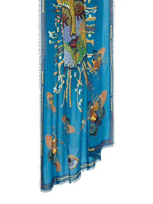 The FRANCO FERRARI - EMBROIDERED SUN WOOL SCARF by FRANCO FERRARI, made in Italy, features a central embroidered sun with rays crafted from various beads and patterns. Surrounding the sun are intricate designs of eyes, butterflies, and abstract motifs, all set against a vibrant blue background with a decorative border.