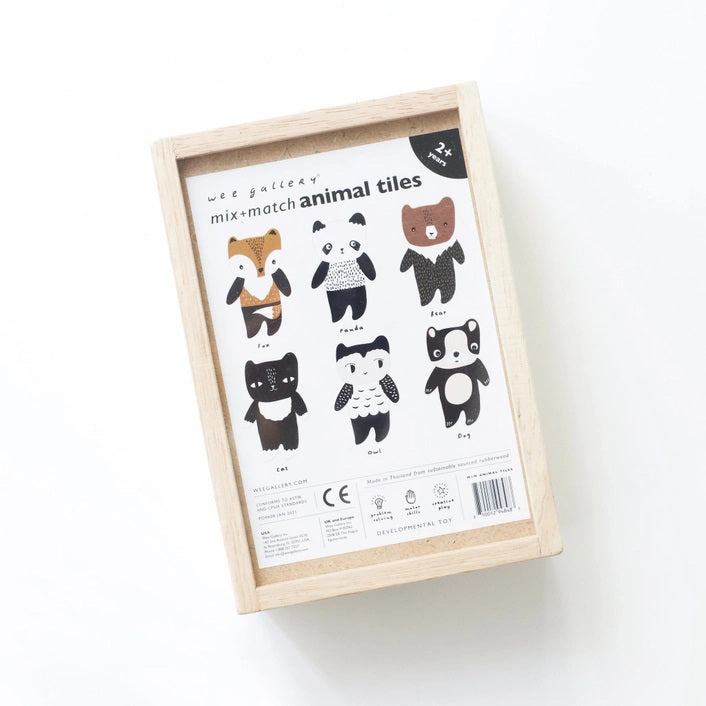 A wooden toy set titled &quot;WEE GALLERY - MIX &amp; MATCH ANIMAL TILES&quot; by WEE GALLERY shown on a white background. The visible toy piece features a cartoonish animal, combining traits of a fox and a bear, painted in brown, white, and black colors. Perfect for creative play and developing motor skills, the toy is presented in a wooden box.