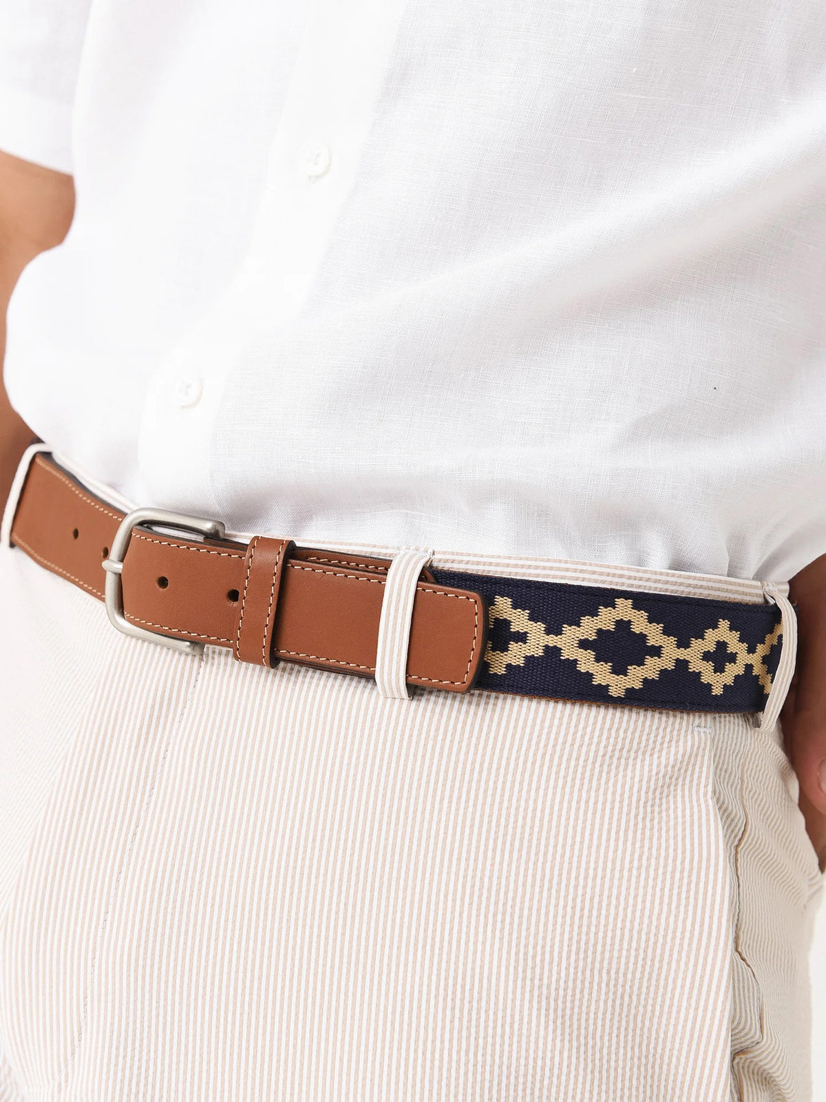 The LA MATERA Corbina Woven Belt features tan genuine leather, a silver buckle, and a navy woven band with a cream geometric diamond pattern.