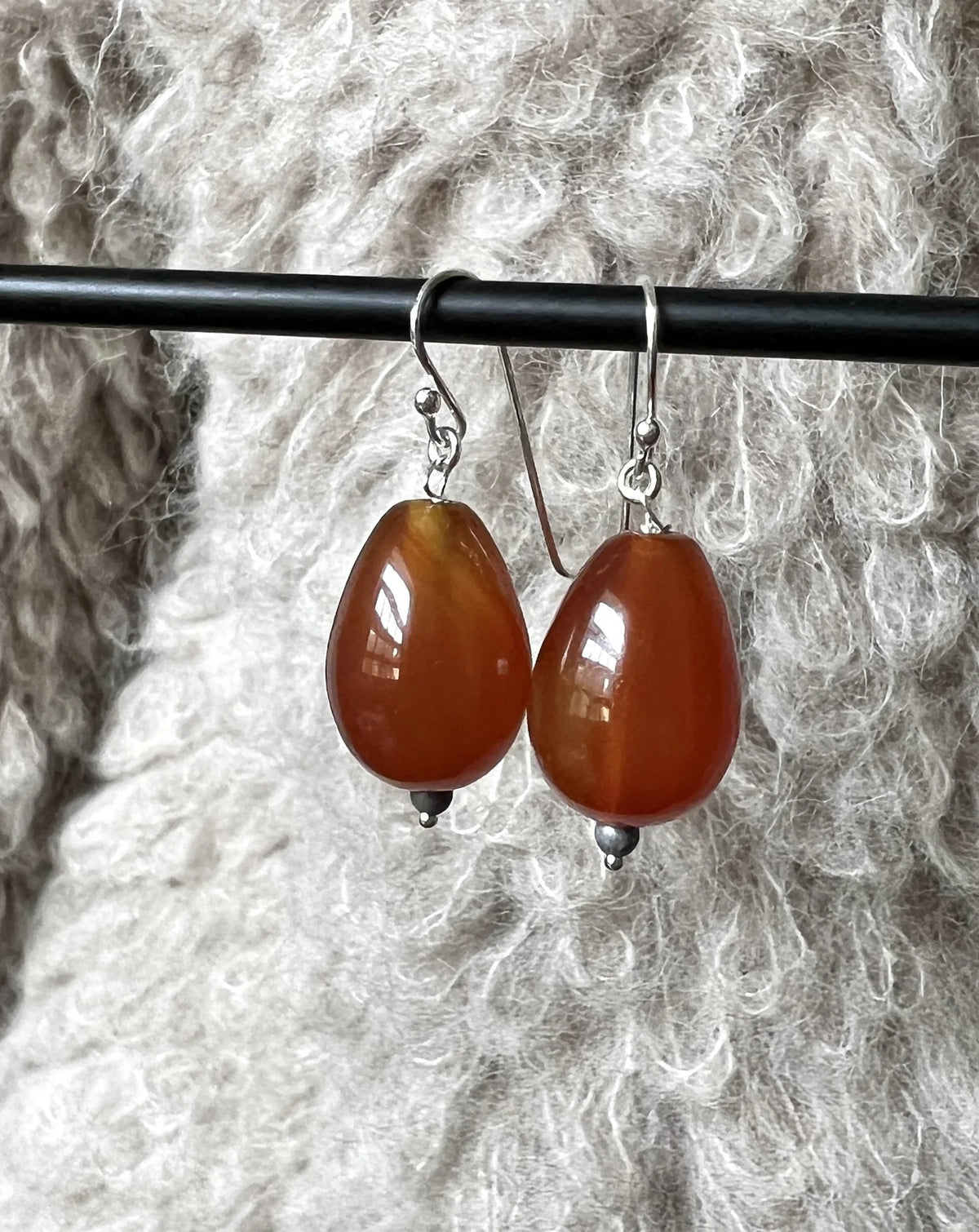 The ANN LIGHTFOOT CARNELIEN TEARDROP EARRINGS feature glossy brown beads with silver accents on sterling silver hooks, shown against a plain white background.