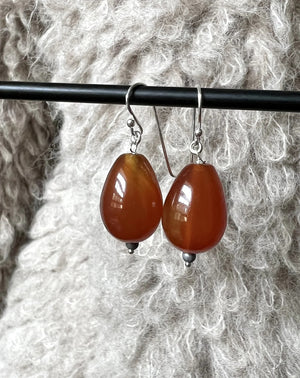 The ANN LIGHTFOOT CARNELIEN TEARDROP EARRINGS feature glossy brown beads with silver accents on sterling silver hooks, shown against a plain white background.