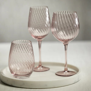 The ZODAX SAVOY OPTIC SWIRL STEMLESS GLASS, featuring a light pink tint and a swirled textured design on the exterior, is depicted against a white background. This rounded glass boasts a smooth, polished finish and ample capacity for your favorite vintage, perfectly capturing elegance in its design.