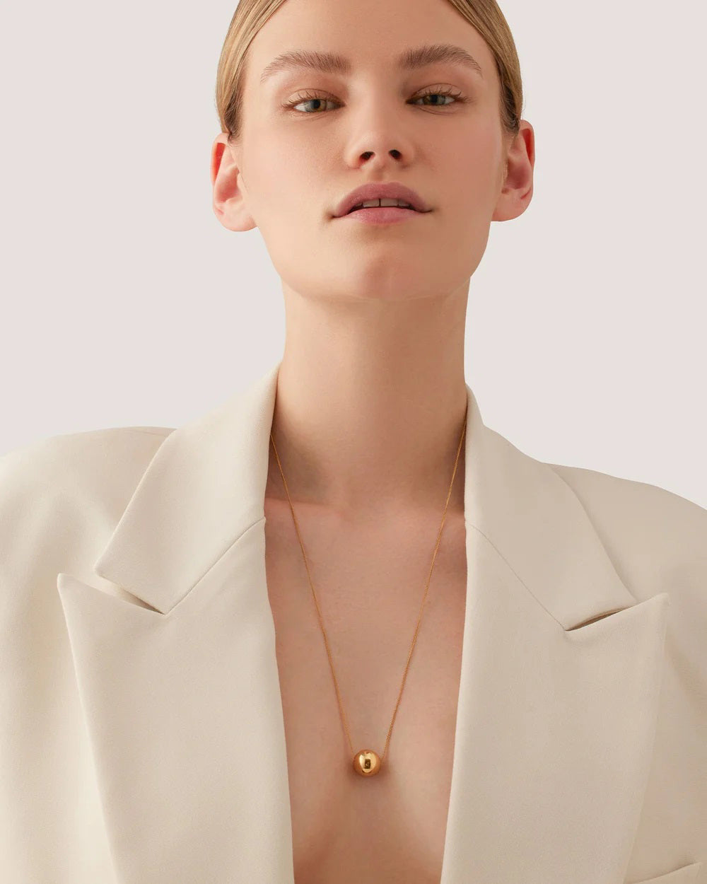 The JENNY BIRD - AURORA PENDANT NECKLACE by JENNYBIRD showcases a delicate chain with a luminous sphere pendant made from high-polish gold, displayed against a plain white background.