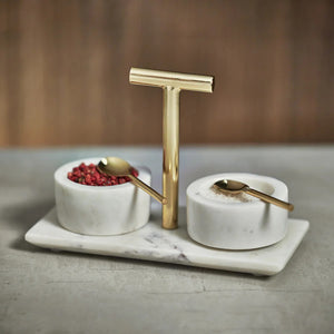 The MARBLE CONDIMENT BOWLS W SPOON by ZODAX, elegantly designed with two round containers on a rectangular base, has product dimensions of 8 in x 3.75 in x 5.75 in. Each container features a small golden spoon and a central T-shaped handle for easy lifting, adding a modern touch to your kitchen decor.