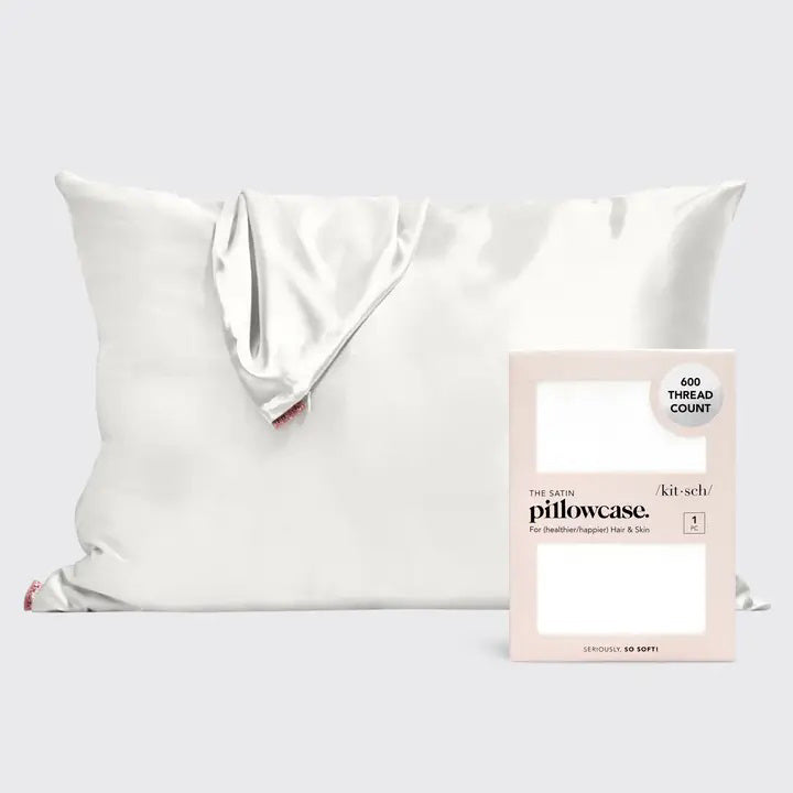 A satin pillowcase with a beige and white leopard print design is displayed against a plain background. To the right of the luxurious pillowcase is its packaging, which reads "SATIN PILLOWCASE" by KITSCH and highlights its 600-thread count and benefits for frizz-free hair and healthy skin.