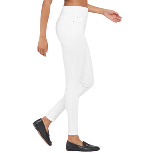 A person wearing the SPANX - SKINNY JEAN, which is a pair of high-waisted white skinny jeans crafted from stretch denim, and black loafers stands against a plain white background. The image focuses on the lower body, highlighting the jeans' high-rise coverage and footwear.