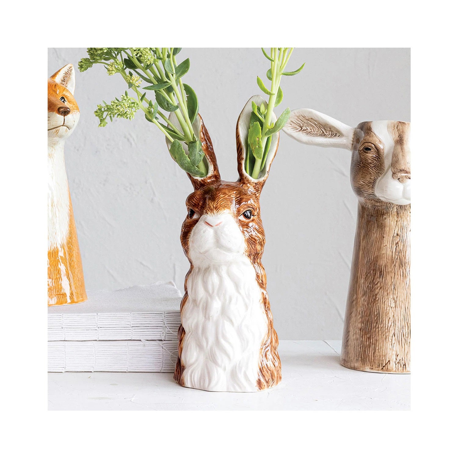 The CREATIVE COOP's RABBIT CERAMIC VASE is hand-painted, showcasing a realistic rabbit with brown fur and upright ears. This farmhouse-style piece captures the calm expression and artistry reminiscent of a classic stoneware vase.