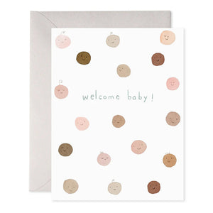 Introducing the "WELCOME BABY GREETING CARD" by E.FRANCES PAPER, featuring a delightful pattern of smiling circles in shades of brown, pink, and beige that resemble faces. A charming whale silhouette enhances the bottom of the design. This card is handcrafted with watercolor accents and is proudly made in the USA. It includes branding details such as "E. Frances," contact information, and a barcode for easy reference.