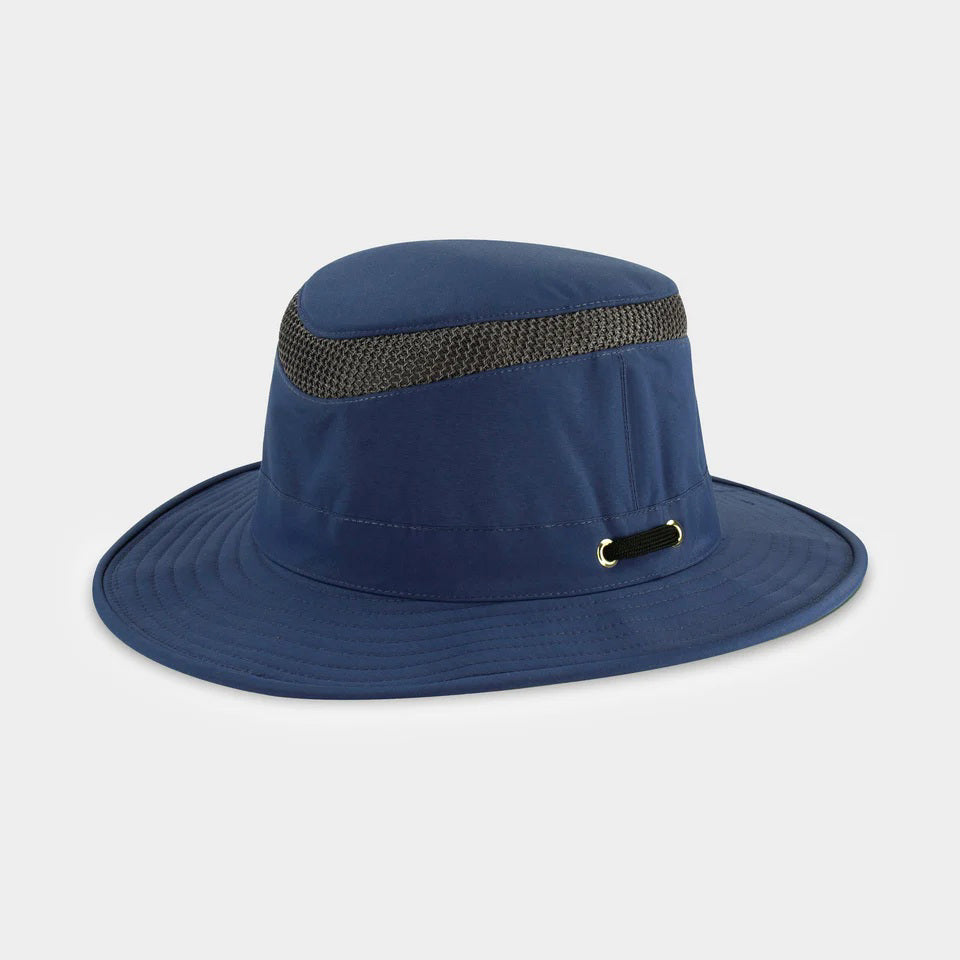 The TILLEY - AIRFLO MEDIUM BRIM LTM5 by TILLEY is a blue hat made from recycled nylon, featuring a black mesh ventilation band around the crown and metal eyelets, shown on a plain light gray background.