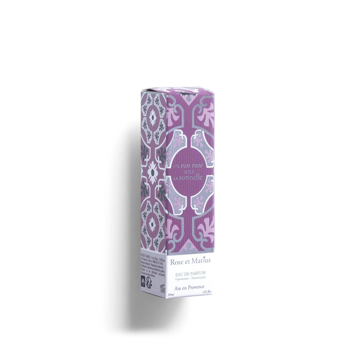A clear 30ml ROSE ET MARIUS - A ROSE WINE UNDER THE ARBOR Eau de Parfum spray bottle, with a pink and white patterned cap beside it, rests on a white background. Soft light casts a gentle shadow to the left.