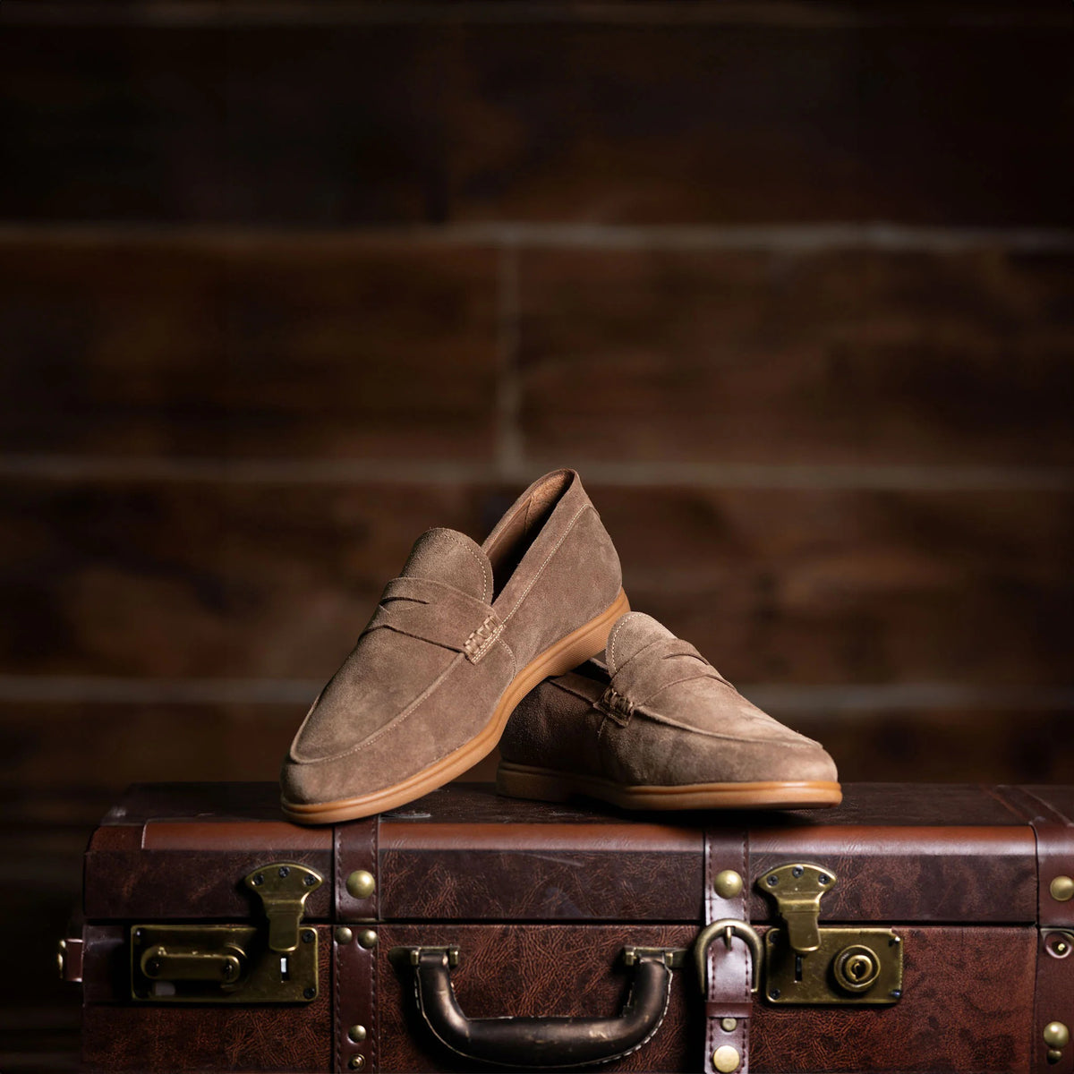 COLLARS AND CO&#39;s Sigaro Penny Loafers in dark tobacco suede are men&#39;s slip-on loafers with low heels, rubber soles, and a decorative strap across the top, shown against a white background.