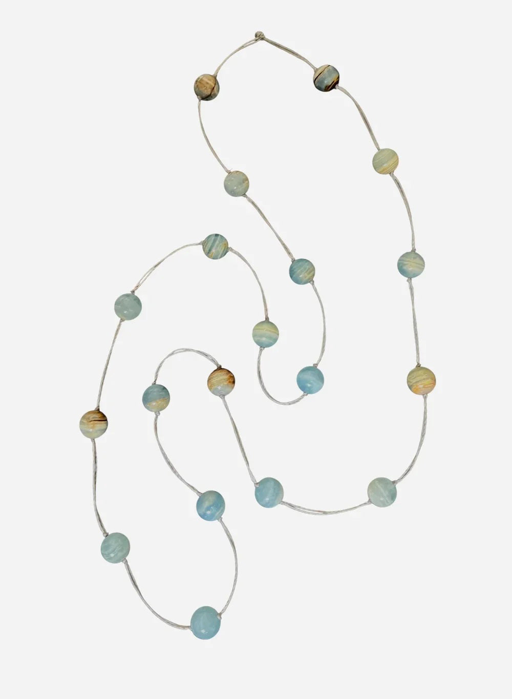 A mannequin in a beige textured sweater showcases the ANN LIGHTFOOT - BLUE CALCITE INTERMITTENT STRAND NECKLACE, a delicate 34&quot; piece with spaced blue and brown beads on a clear strand. The softly blurred background highlights the jewelry.