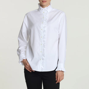 A person wearing the HINSON WU - NORA SHIRT, a luxe cotton blouse with delicate ruffles adorning the collar and cuffs, paired with black pants. This tailored shirt by HINSON WU features a button-up front with exquisite ruffle trim against a plain light background.