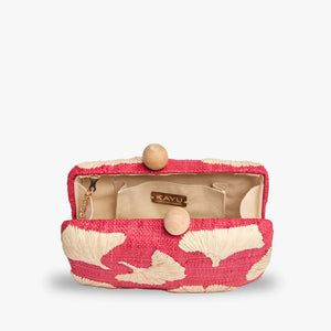 The KAYU - AMI CLUTCH is a rectangular raffia clutch in red and beige with abstract leaf designs and two wooden ball clasps.