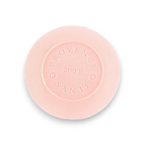 A round, pale pink bar of French-milled soap from Baudelaire, embossed with "Provence Santé" and "200 g", infused with the essence of wild rose. This luxurious bath bar is part of the Baudelaire Wild Rose collection and comes in a 7 oz boxed presentation.