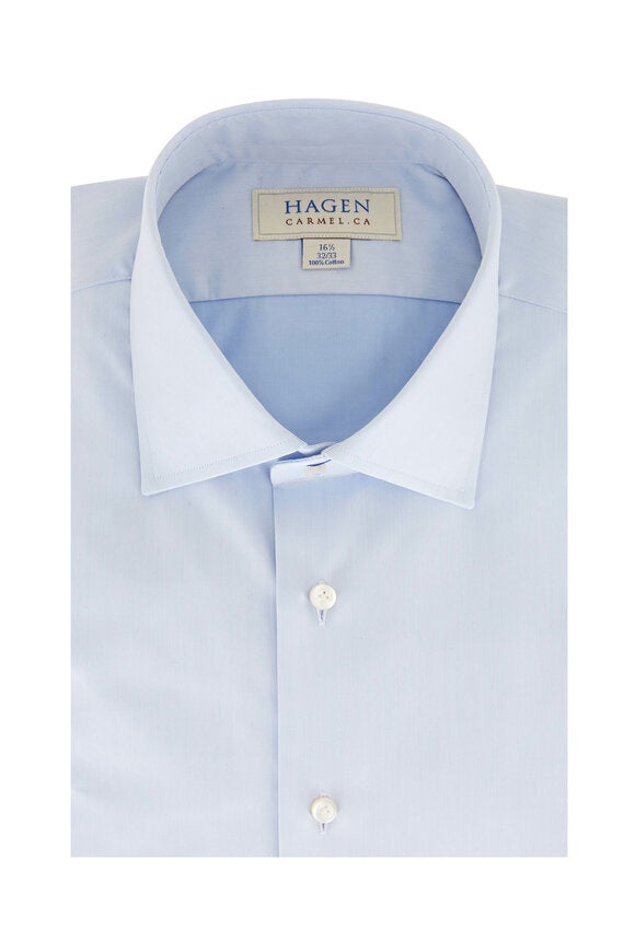The HAGEN - COTTON DRESS SHIRT IN LIGHT BLUE is neatly folded, featuring a modern spread collar, white buttons, and premium cotton. The label inside the collar displays &quot;Hagen Carmel, CA&quot; with size details.
