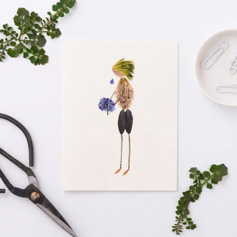 The PETAL PEOPLE PRESS - WITH SYMPATHY CARD by PETAL PEOPLE PRESS features a whimsical figure crafted from leaves and seeds, resembling a person holding a bouquet of Forget-Me-Not blue flowers. The head is fashioned from a green leaf, the body from a textured seed, and the legs and feet are thin twigs, making it perfect for adding delicate beauty to any sympathy card.