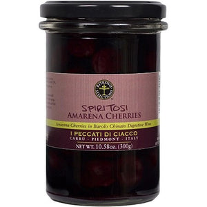 Displayed is a jar of RITROVO AMARENA CHERRIES IN BAROLO CHINATO. The jar is adorned with a black lid and a pink label accented in black and gold. Highlighted on the label are the product name, brand, and net weight of 10.58 oz (300g). Savor the rich herbal flavor accentuated by Barolo Chinato notes.