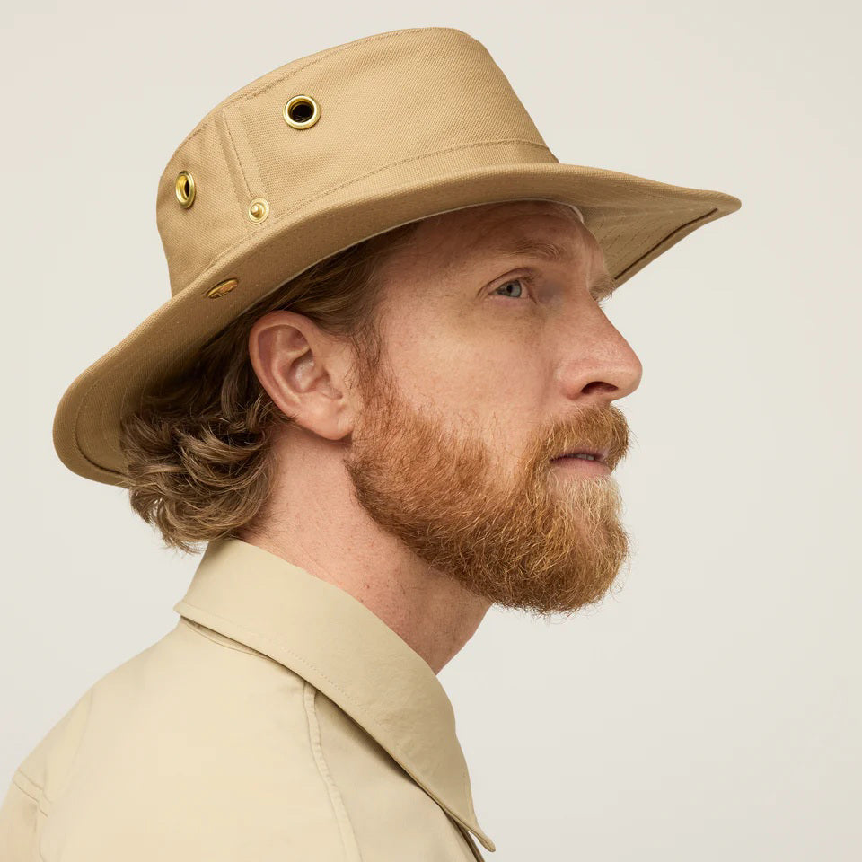 A man with a red beard and mustache wears a TILLEY - CLASSIC T3 HAT in tan, featuring UPF 50+ protection, and a matching buttoned shirt, facing the camera against a plain light background.