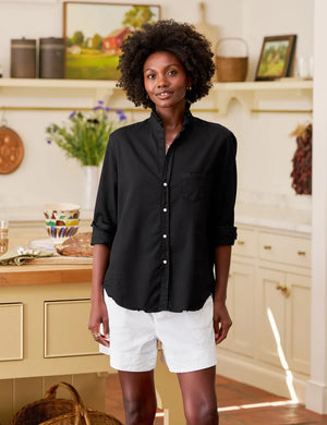 The FRANK & EILEEN Ruffle Eileen Ruffle Collar Button Up Shirt in Famous Denim Blackout features long sleeves, white buttons, a single chest pocket, and a ruffled collar, shown laid flat against a white background.
