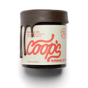 A 10 oz (283.5 g) jar of COOPS - PEPPERMINT HOT FUDGE, handcrafted in small batches. It features a minimalist design with a brown lid and dripping fudge effect. Made from European chocolate infused with peppermint oil, it offers a smooth and cool taste.