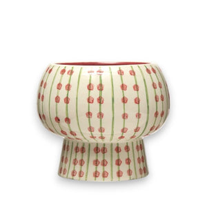 The PLANTER WITH PATTERN by CREATIVE COOP is a hand-painted stoneware ceramic vase that features a rounded bowl shape with a smaller cylindrical base. It is adorned with vertical green lines and small red flowers on a cream-colored background, giving it a vibrant and artistic appearance.