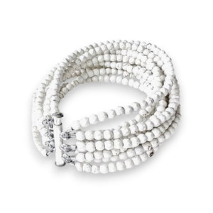 The ANN LIGHTFOOT - 9 STRAND WHITE TURQUOISE CUFF BRACELET by ANN LIGHTFOOT is a sophisticated accessory featuring multiple strands of 4mm white turquoise beads. This bracelet showcases a sterling silver clasp that elegantly holds the intertwined strands together, emphasizing its clean and minimalistic design. The simplicity and beauty of this piece make it a timeless addition to any jewelry collection.