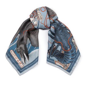 The SABINA SAVAGE - KOINOBORI KARASU SILK TWILL SCARF 90CM from SABINA SAVAGE ENGLAND is crafted with a detailed design showcasing a prominent bird amidst an intricate pattern of abstract shapes, reminiscent of waves inspired by Hokusai, in shades of blue, black, and orange. The scarf is finished with elegant edges featuring intricate borders and stylized motifs.