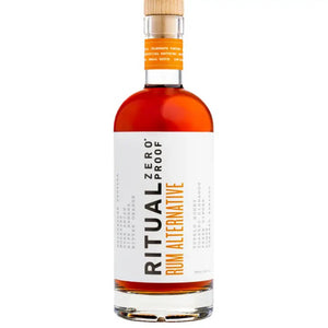 A bottle of RITUAL ZERO PROOF - Rum Alternative, a non-alcoholic rum. The bottle is capped with a cork and adorned with a white label showcasing the brand's name, RITUAL ZERO PROOF, prominently in black and orange text. Inside, the amber liquid offers flavors of vanilla, toffee, and spice.