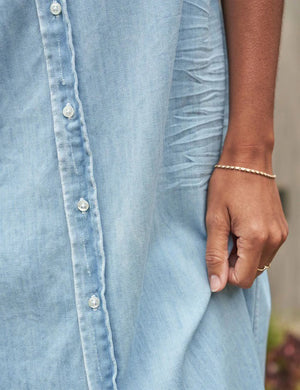 The FRANK & EILEEN Rory Maxi Shirtdress in Famous Denim is a full-length button-up dress featuring a collar, rolled-up sleeves to mid-length, and a single chest pocket. Its sleek, minimalist design embodies that California chic look against a plain white textured background.