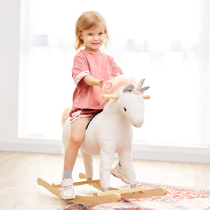 The WONDER AND WISE ASWEETS UNICORN ROCKER features a white fabric unicorn with a unicorn horn, light pink mane and tail, and a light pink saddle. Mounted on a wooden rocker base, it includes magical details such as stitched eyes and a small side pocket for added comfort.