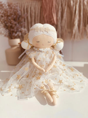 Introducing the ALIMROSE - WILLOW FAIRY DOLL by ALIMROSE: This enchanting plush fairy doll features a serene expression, white wings trimmed with gold, and a star-adorned dress. Adorned with white hair accented by a golden headband and bow, and wearing gold ballet shoes, this ethereal beauty makes an exquisite addition to nursery decor or a special gift for any little one.