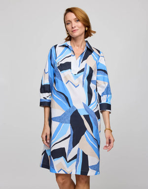 A person is wearing the HINSON WU - VICKY 3/4 SLEEVE ABSTRACT PRINT DRESS, which boasts a bold, exclusive print in blue, white, and black on refined cotton. The knee-length dress features 3/4 sleeves and a collar. The individual has short light brown hair against a plain background.