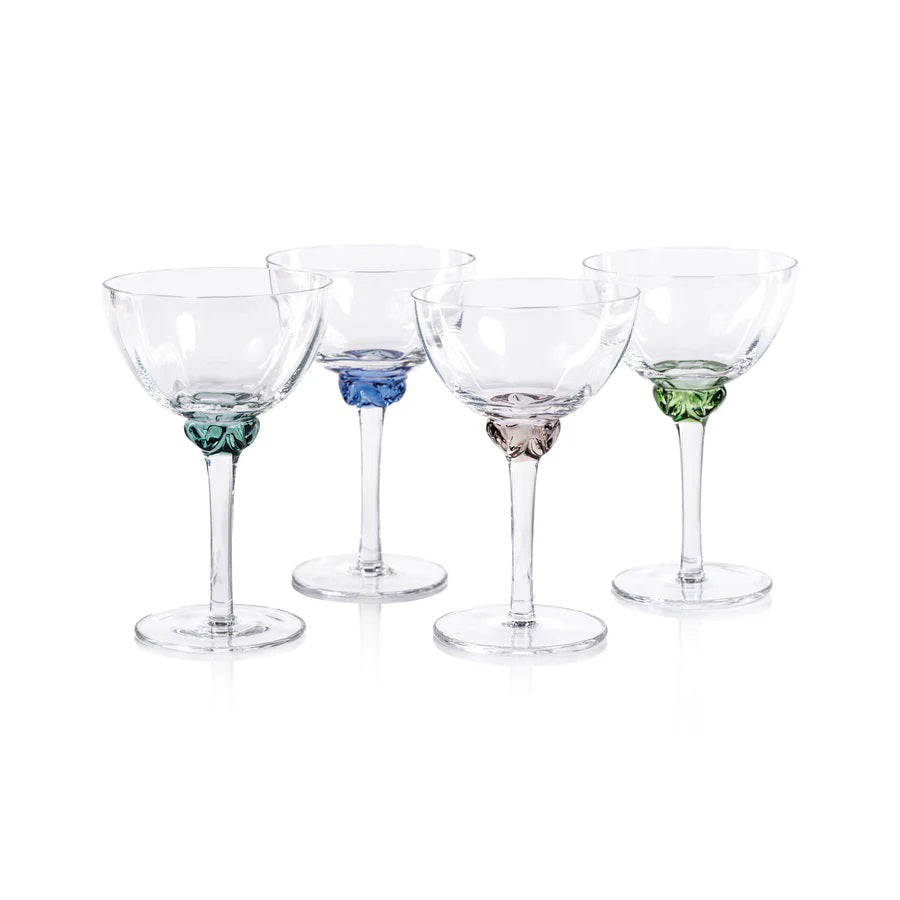 Introducing the MARTINI COCKTAIL OPTIC GLASS set by ZODAX: a collection of four elegant cocktail glasses featuring clear bowls with colorful accents. Each glass boasts a wide bowl and a slender stem, with bases in distinct colors—green, blue, gray, and light pink—perfect for showcasing the dimensions and capacity of your cocktails in style.