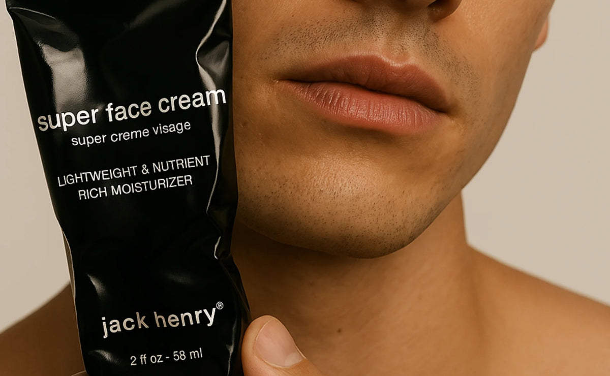 A black tube of JACK HENRY - SUPER FACE CREAM, branded with &quot;JACK HENRY&quot; in white text and topped with a black cap, rests on a white background casting a right-side shadow—a minimalist moisturizer ideal for anti-aging skincare.